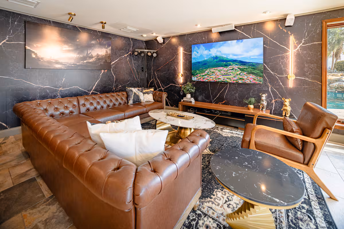 Great room with leather sectional, stone media wall, and timber ceiling